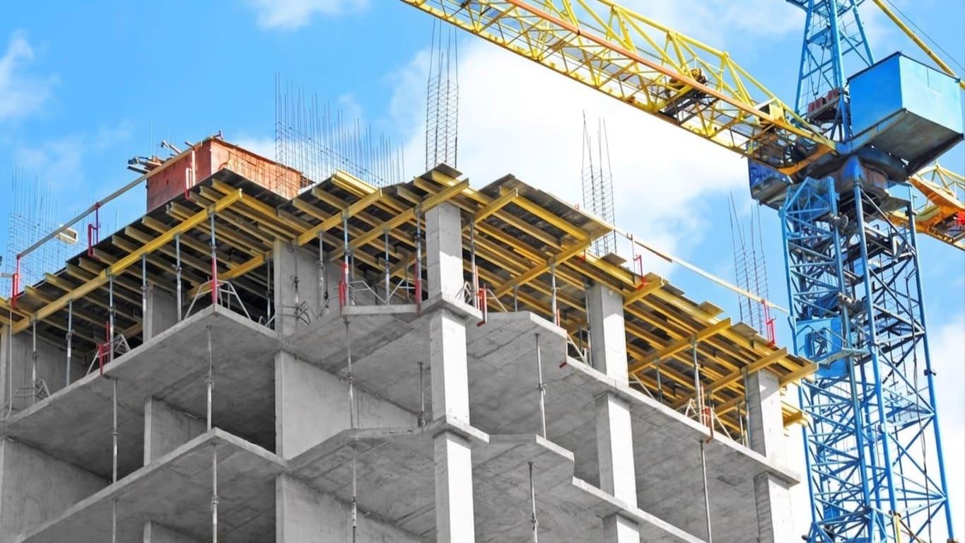 Chantier de construction avec grues et structure en béton, illustrant la garantie Tous Risques Chantier
